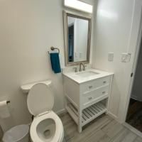 A bathroom with a toilet , sink , mirror and trash can.