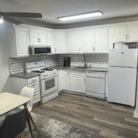 A kitchen with white cabinets , a stove , a refrigerator , and a ceiling fan.