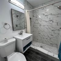 A bathroom with a toilet , sink , shower and mirror.