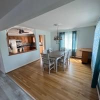 A dining room with a table and chairs and a kitchen in the background.