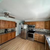 A kitchen with wooden cabinets , stainless steel appliances , and a ceiling fan.