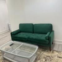 A green couch is sitting next to a glass coffee table in a living room.