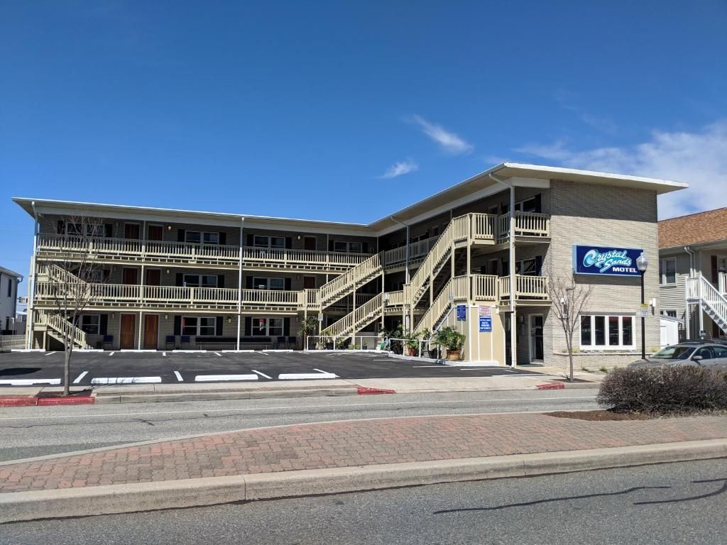 A motel with cars parked in front of it and a vacancy sign.