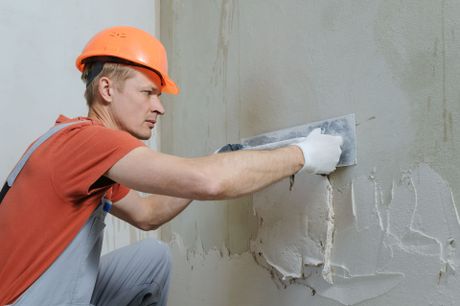 a man is plastering a wall with a trowel .
