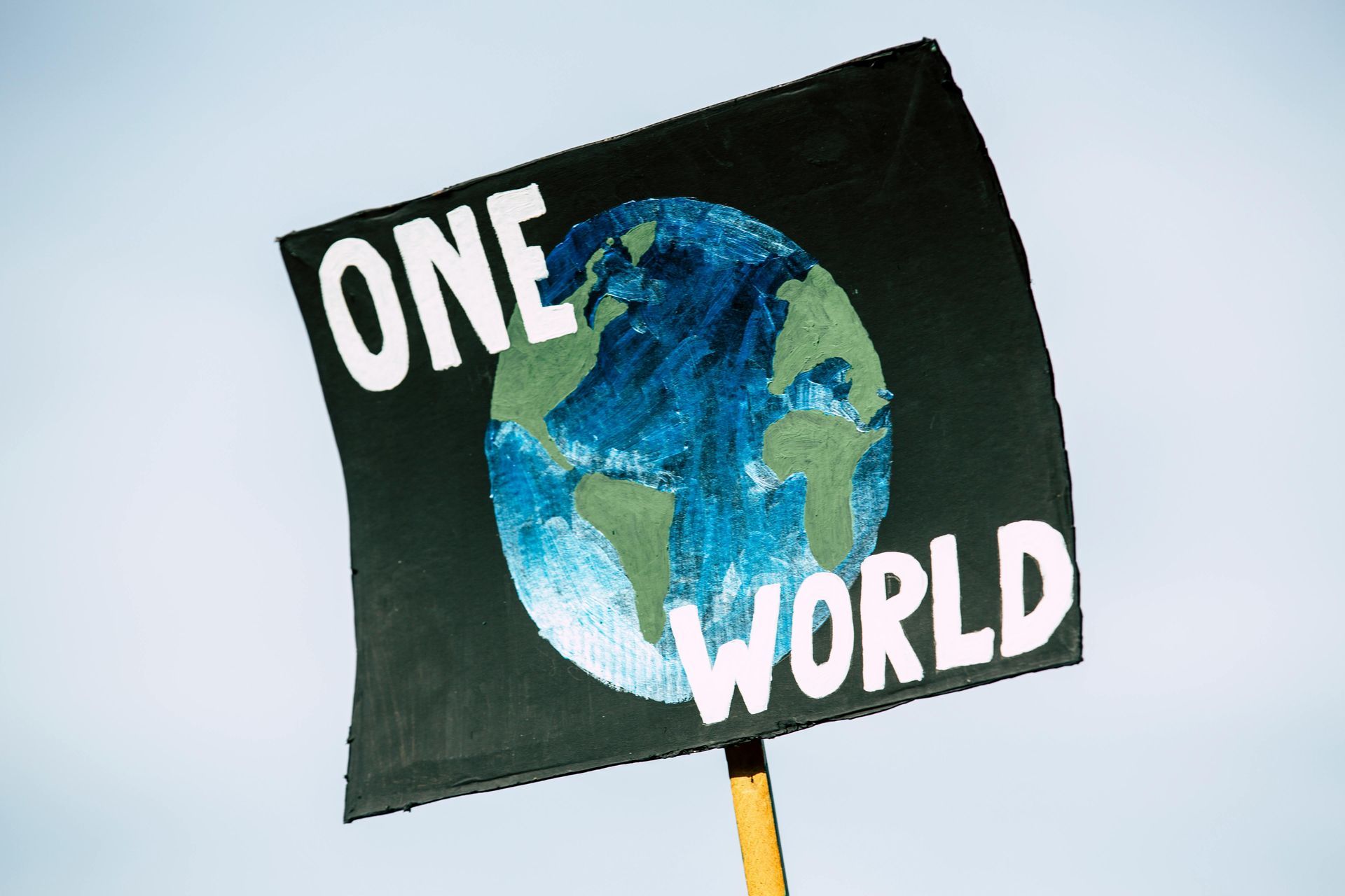 One World text with an image of the earth sign