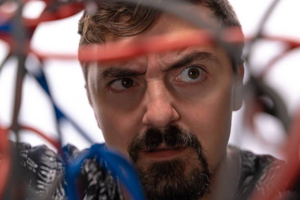 Person in patterned jacket amid tangled red and blue wires.