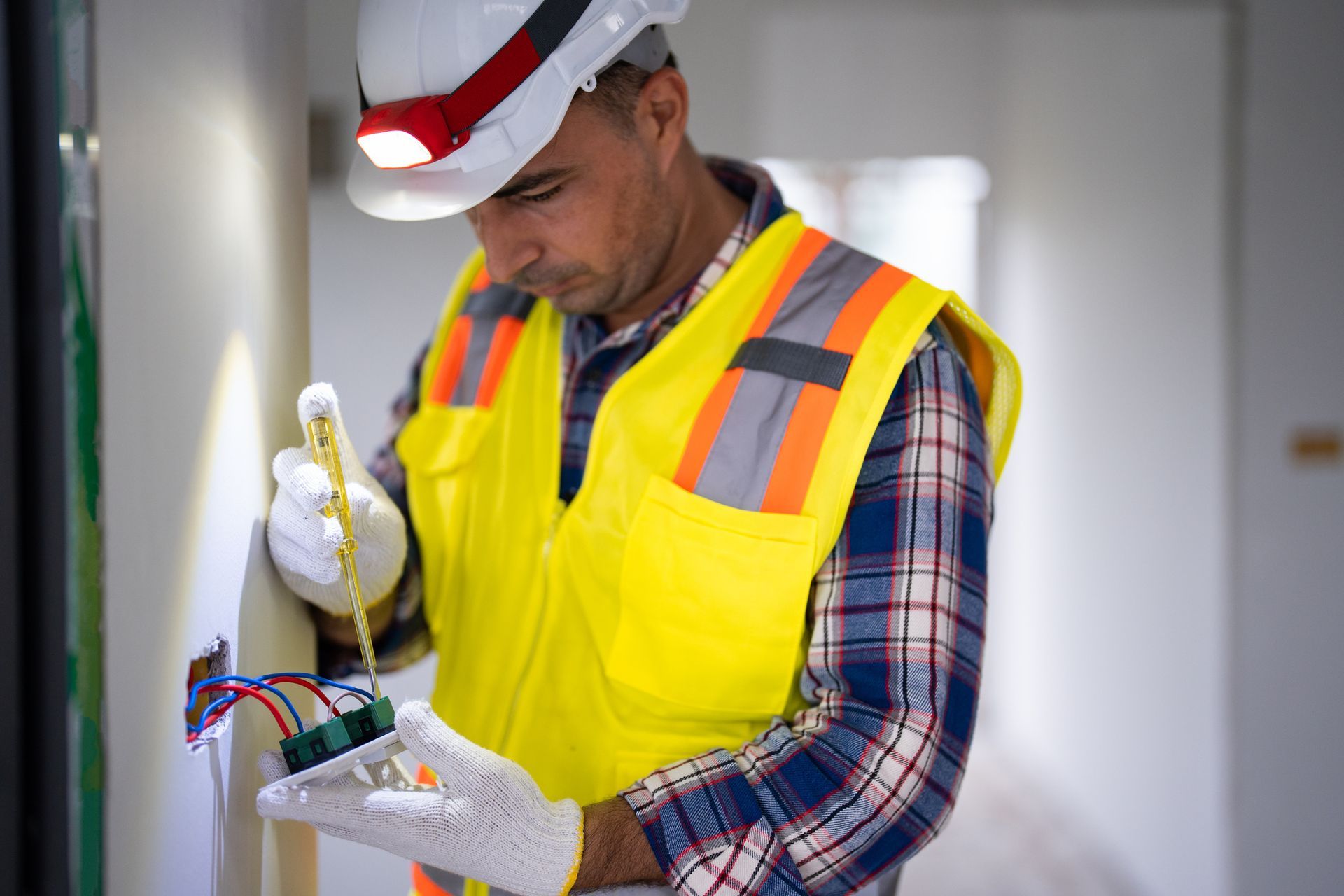 An electrician prepares and installs electrical wiring in a residential home