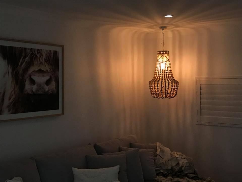A room with a framed cow portrait, a beaded pendant light, and a couch.— Quik Fire Electrical in Kelmscott, WA