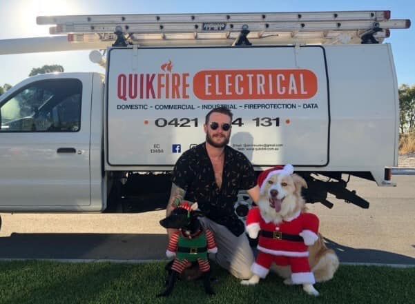 Man and two dogs in Christmas outfits in front of a