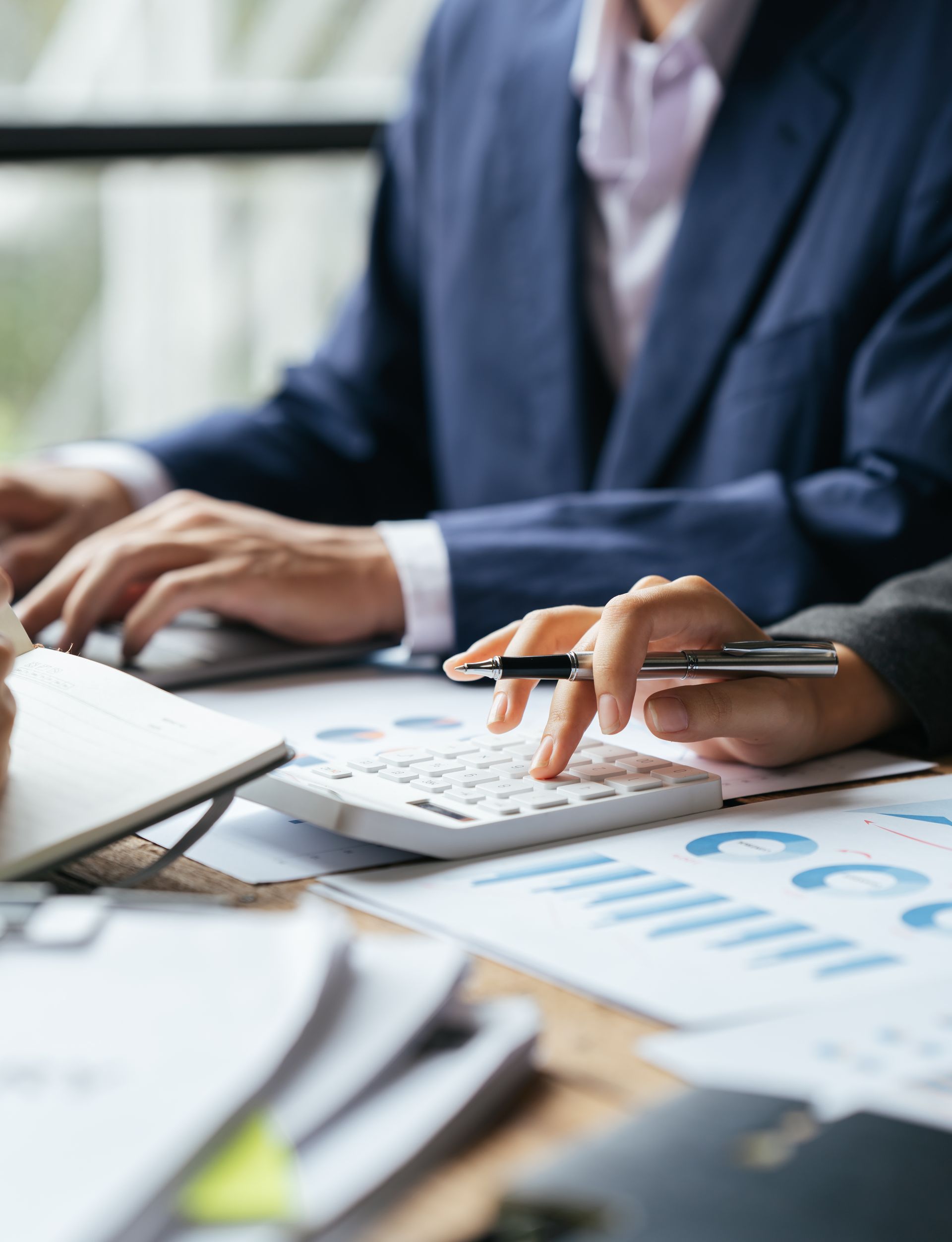 Des personnes travaillant avec une calculatrice, des documents et un ordinateur portable, probablement dans un bureau.
