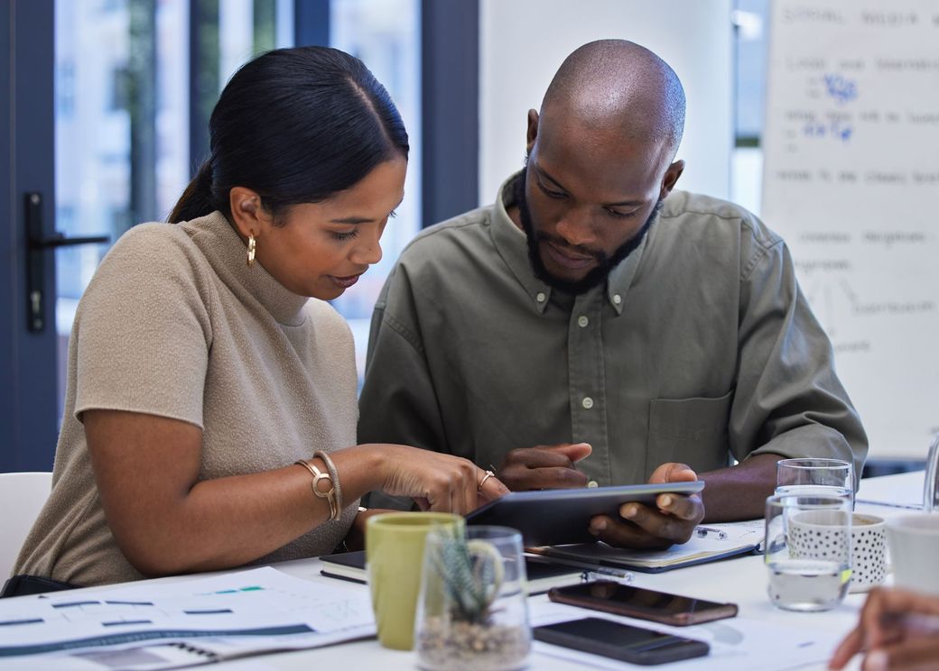 Deux personnes regardent une tablette ensemble dans un bureau.