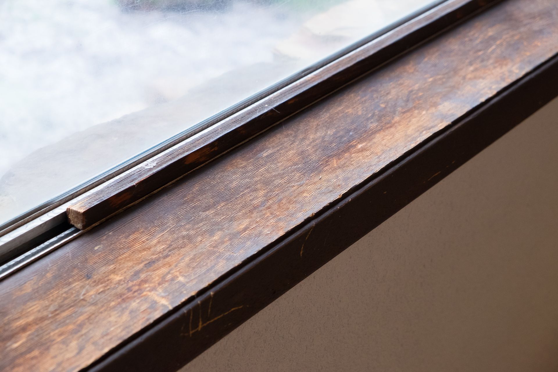 Wooden window sill with visible wood grain and a metal track; angled view.