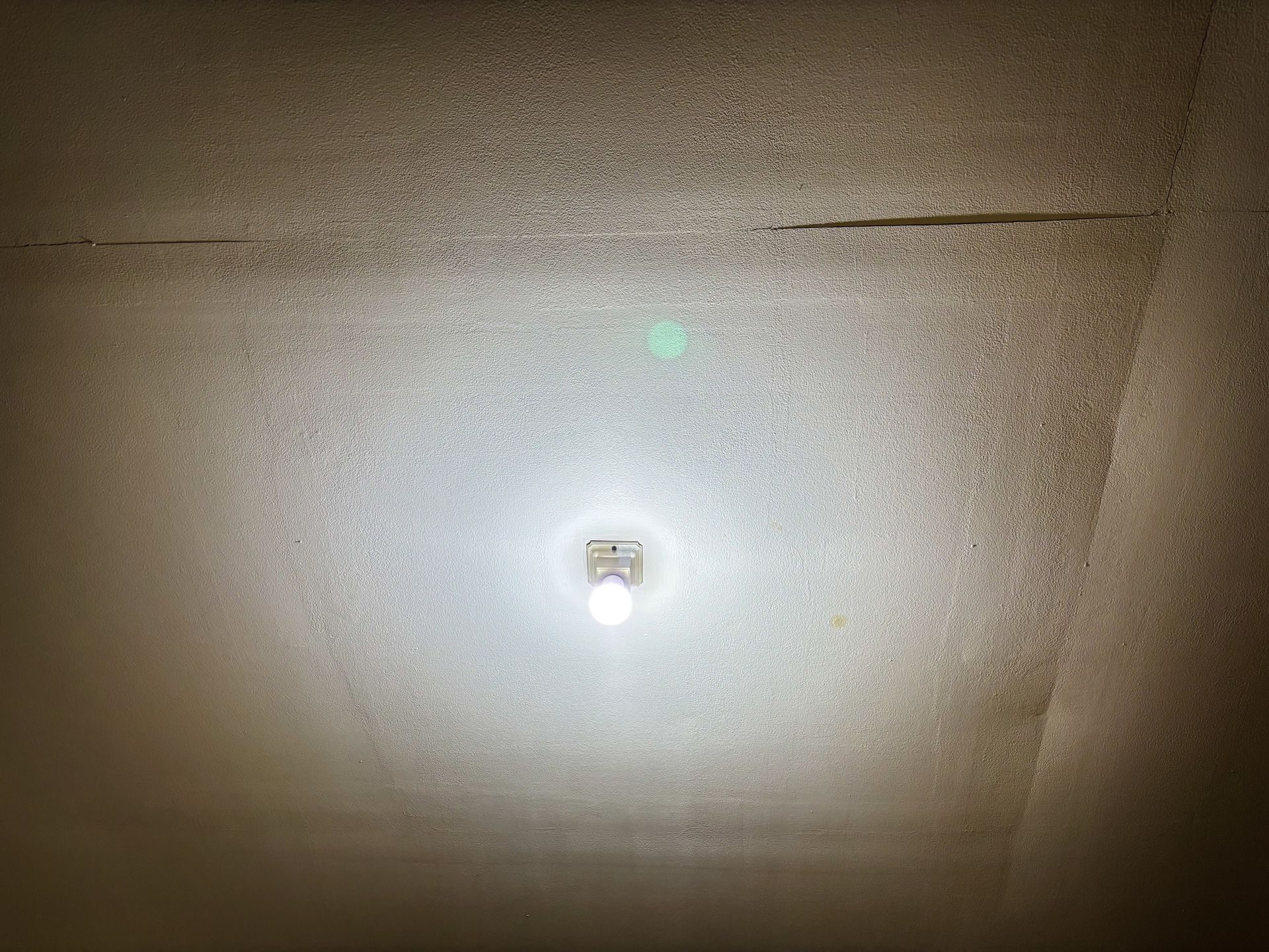 A textured ceiling with a light fixture in the center, a crack across the top.