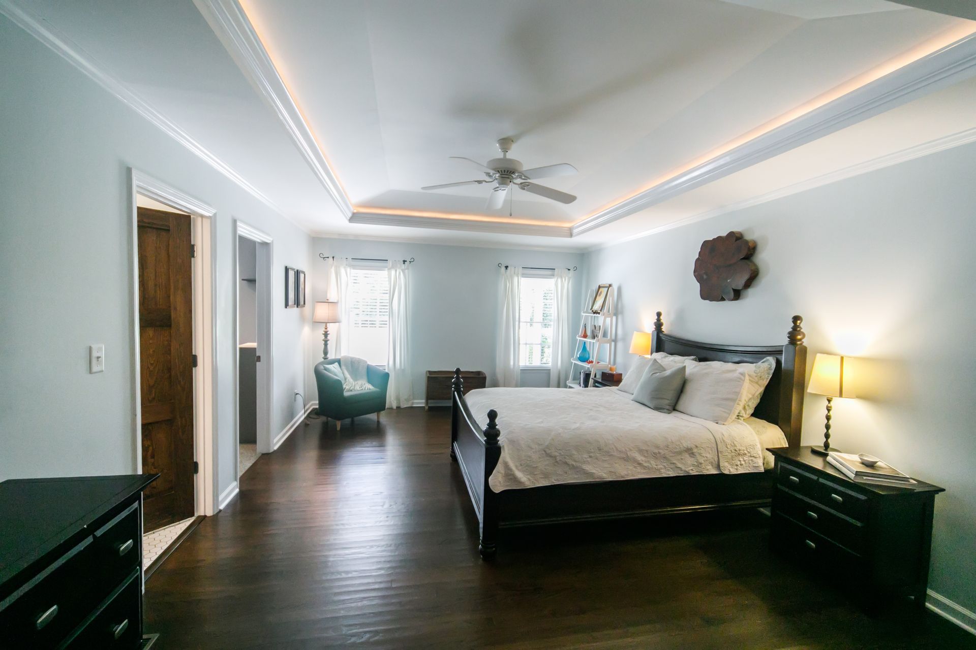 Bedroom with dark wood bed, ceiling fan, and blue-gray walls, wood floor, and recessed lighting.