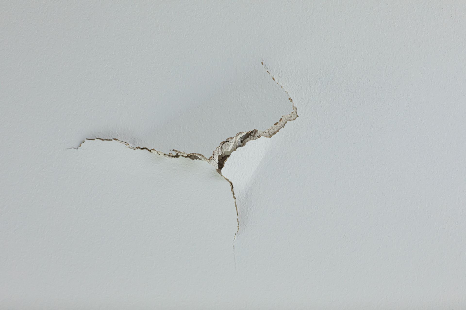 White ceiling with a large crack and peeling paint.