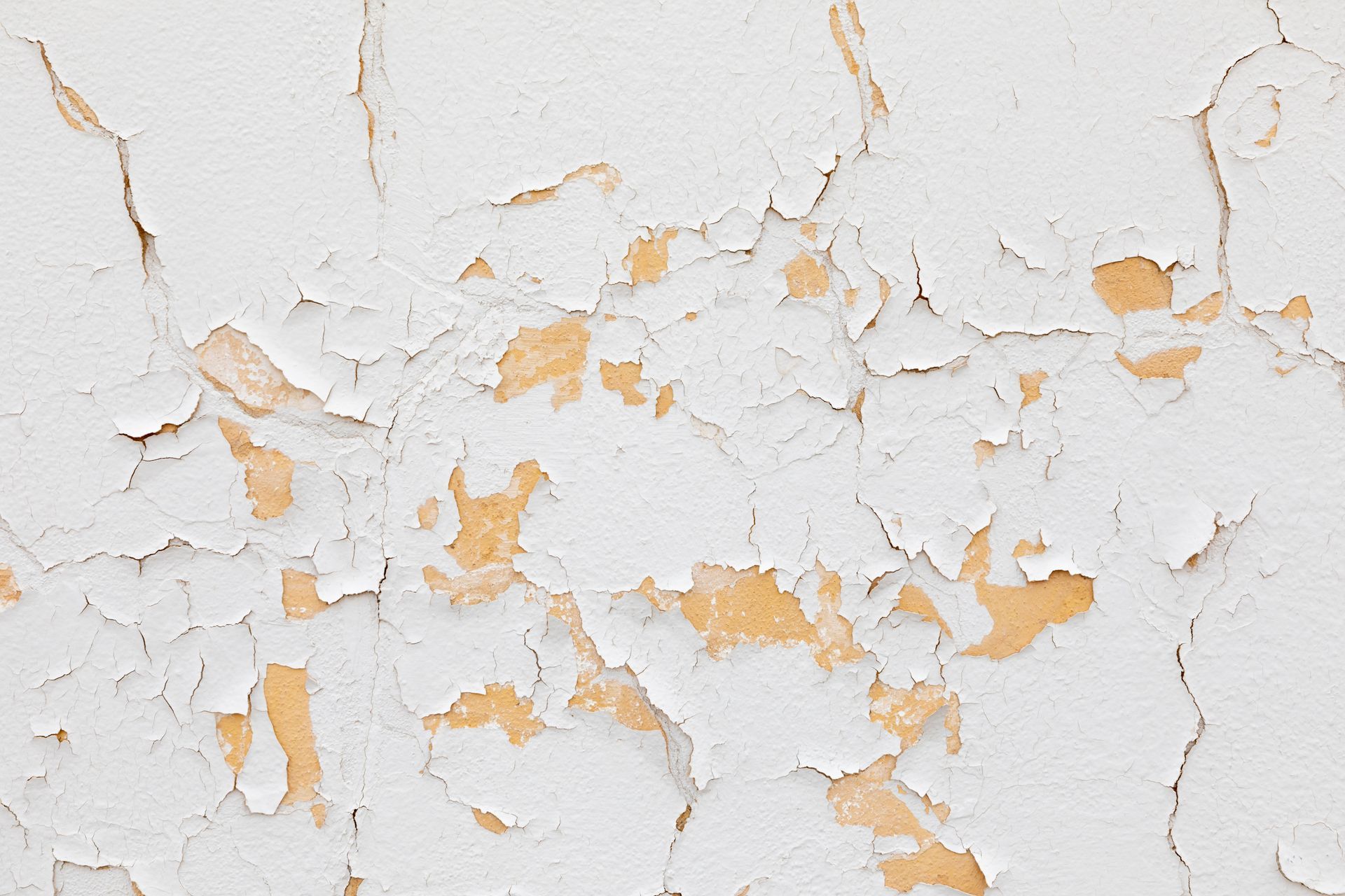 White paint peeling off a light orange wall.