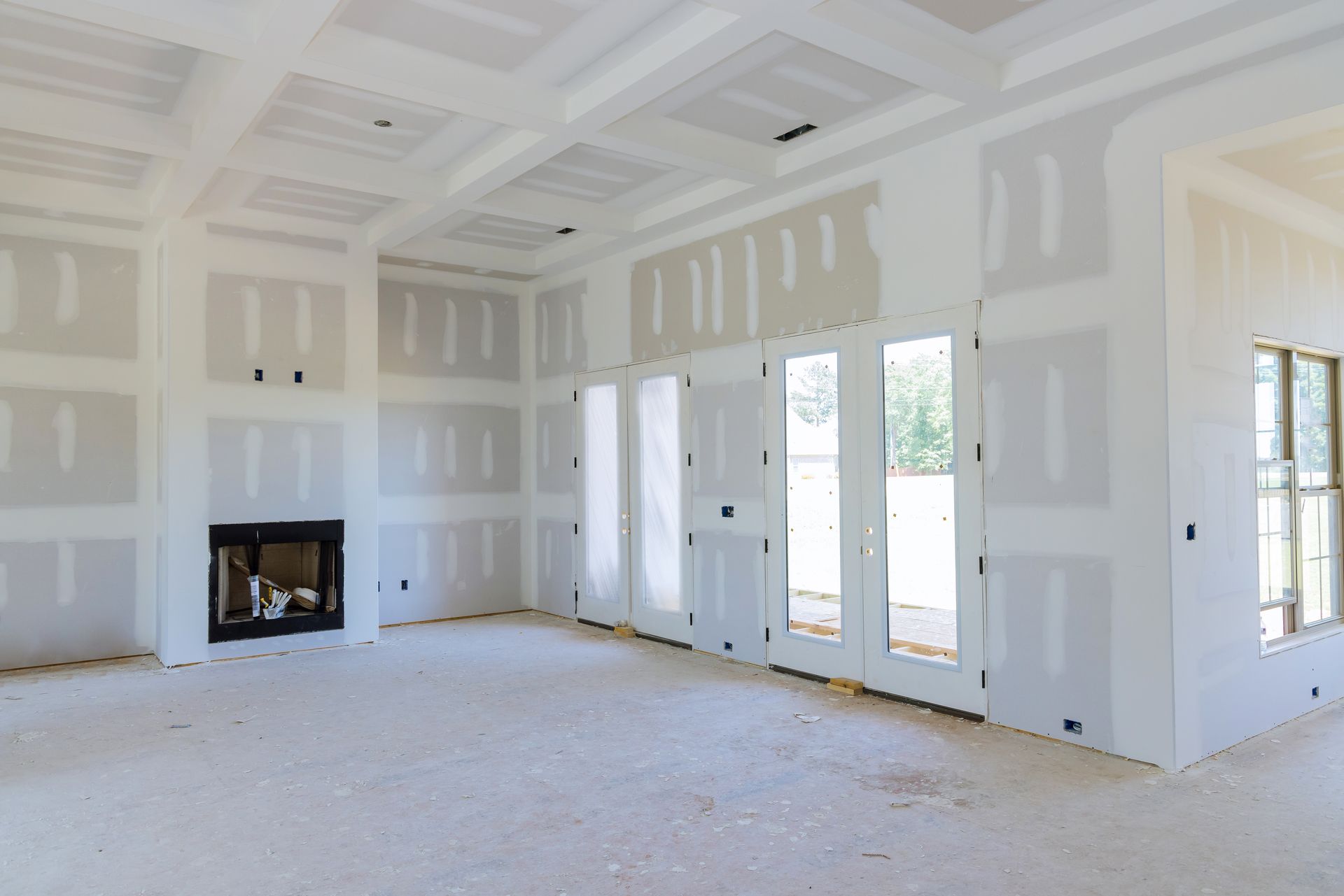 Interior room with drywall on walls and ceiling, fireplace, and French doors.