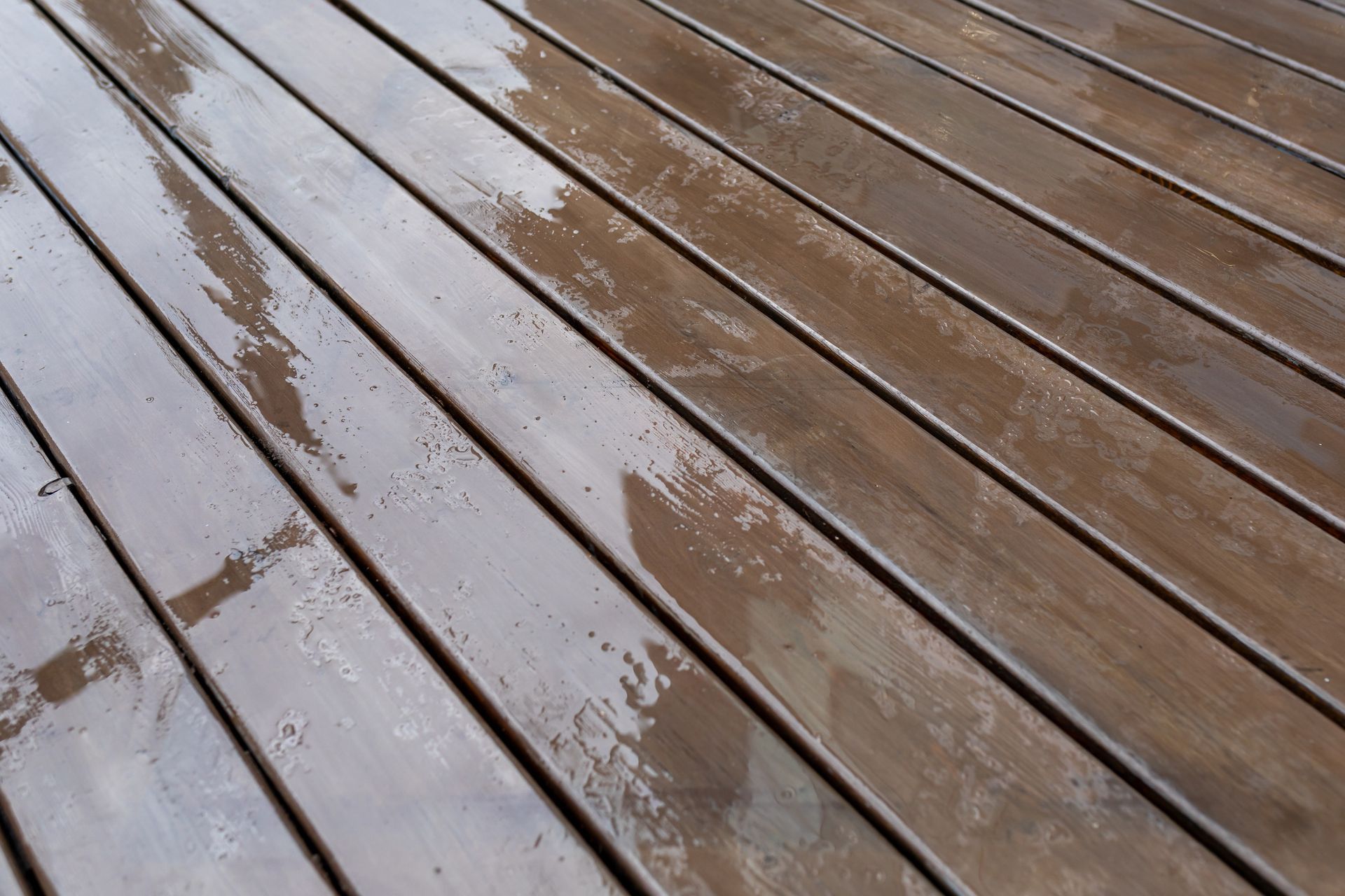 Wet wooden deck boards, brown with water glistening on the surface.