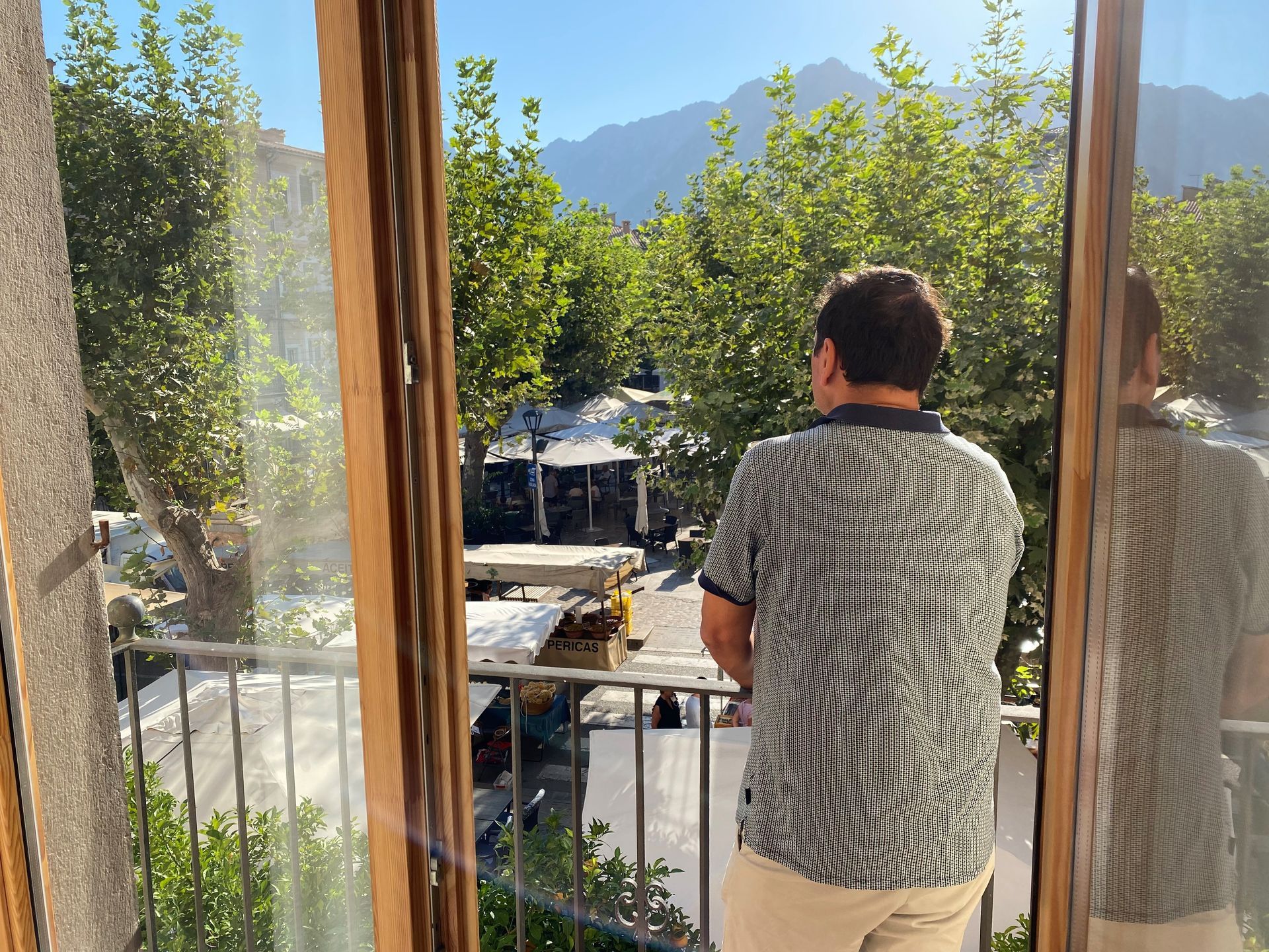 the boss on balcony looking at mountain view; trees and bright sunlight.