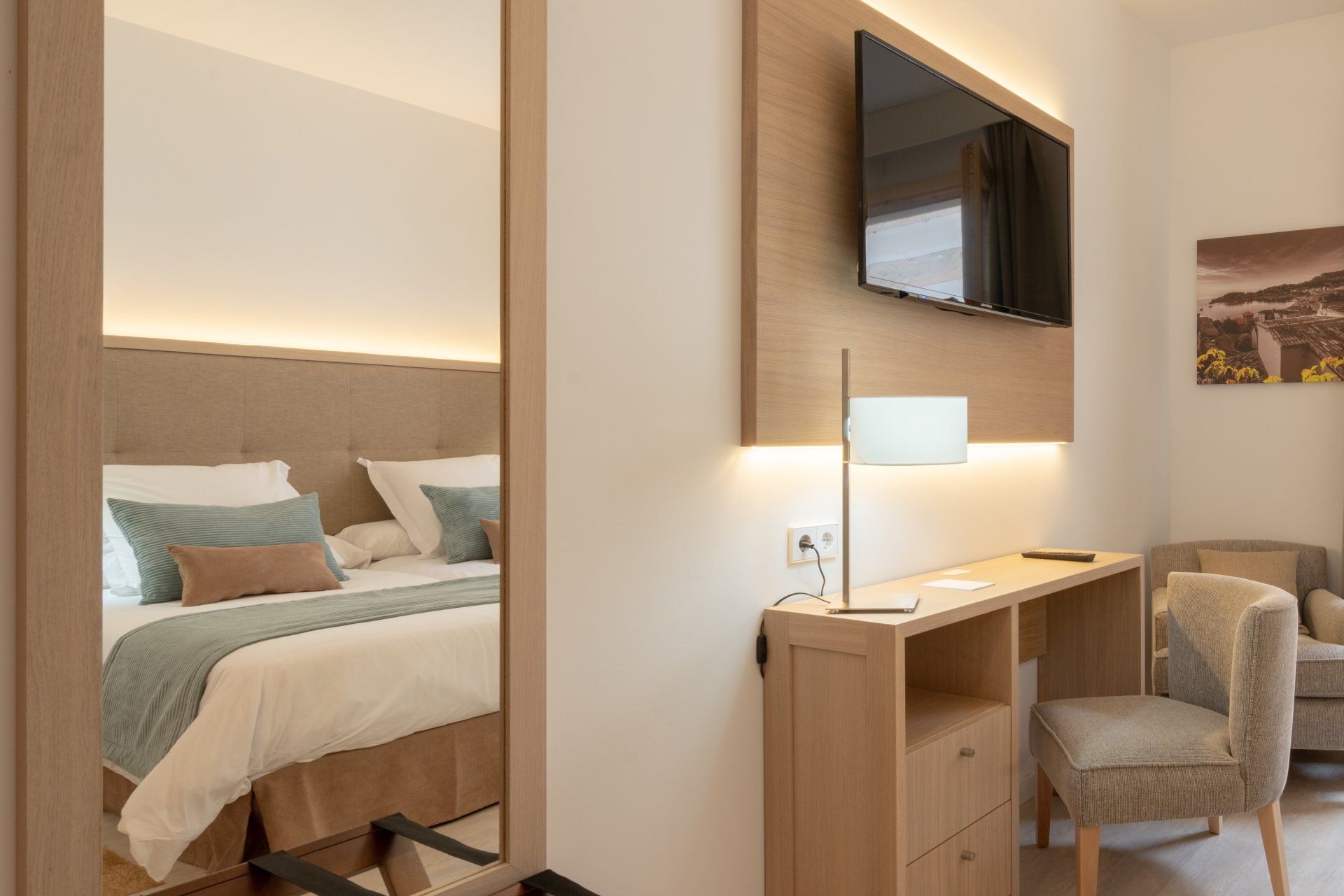 Intérieur d'une chambre d'hôtel avec lit, bureau et télévision. Tons neutres et design moderne.