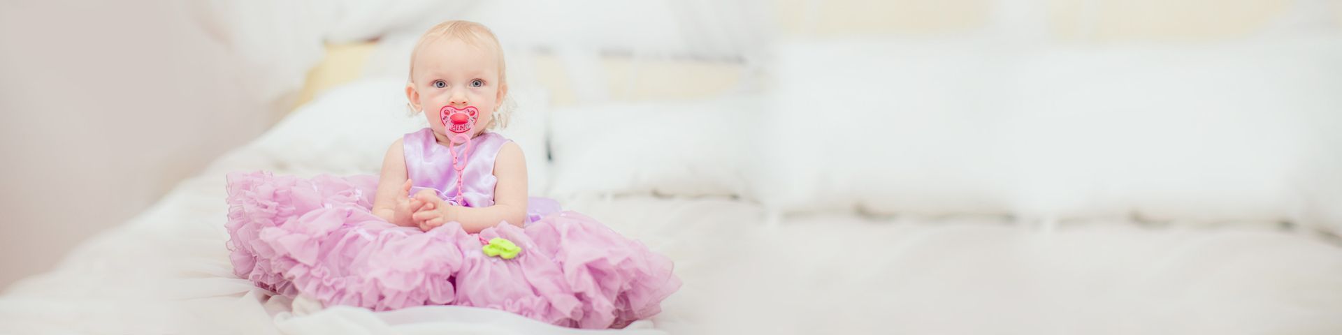 a baby in a purple dress with a pacifier in her mouth