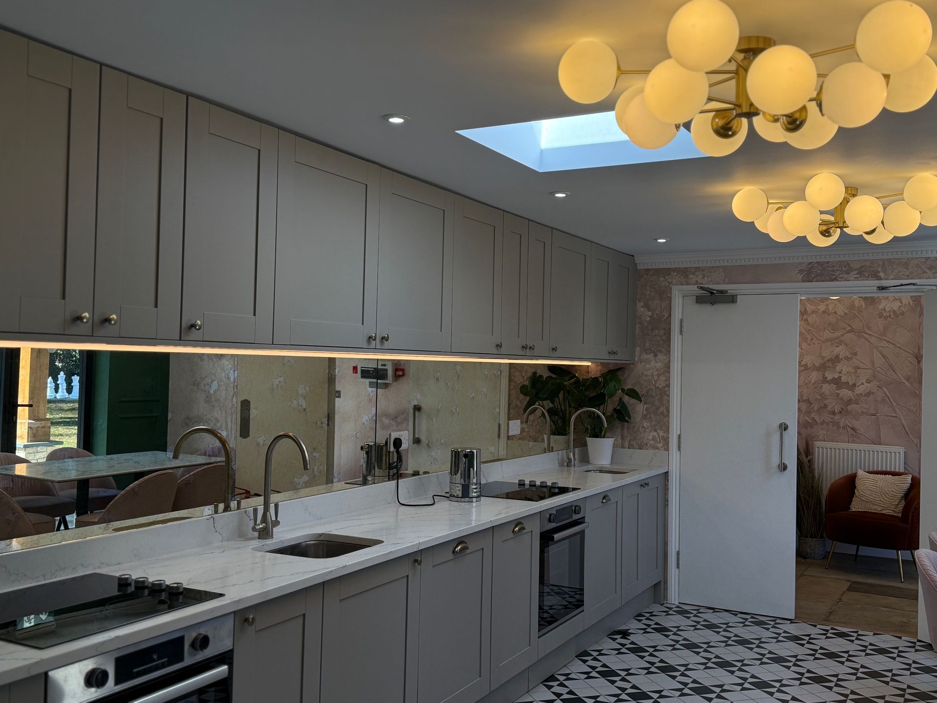 Modern kitchen with gray cabinets, white countertops, and decorative lighting.