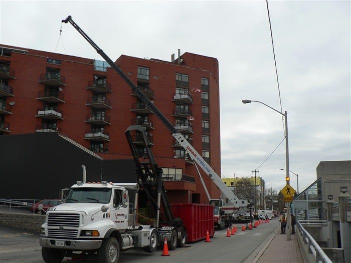 A truck with a crane attached to it is parked in front of a brick building