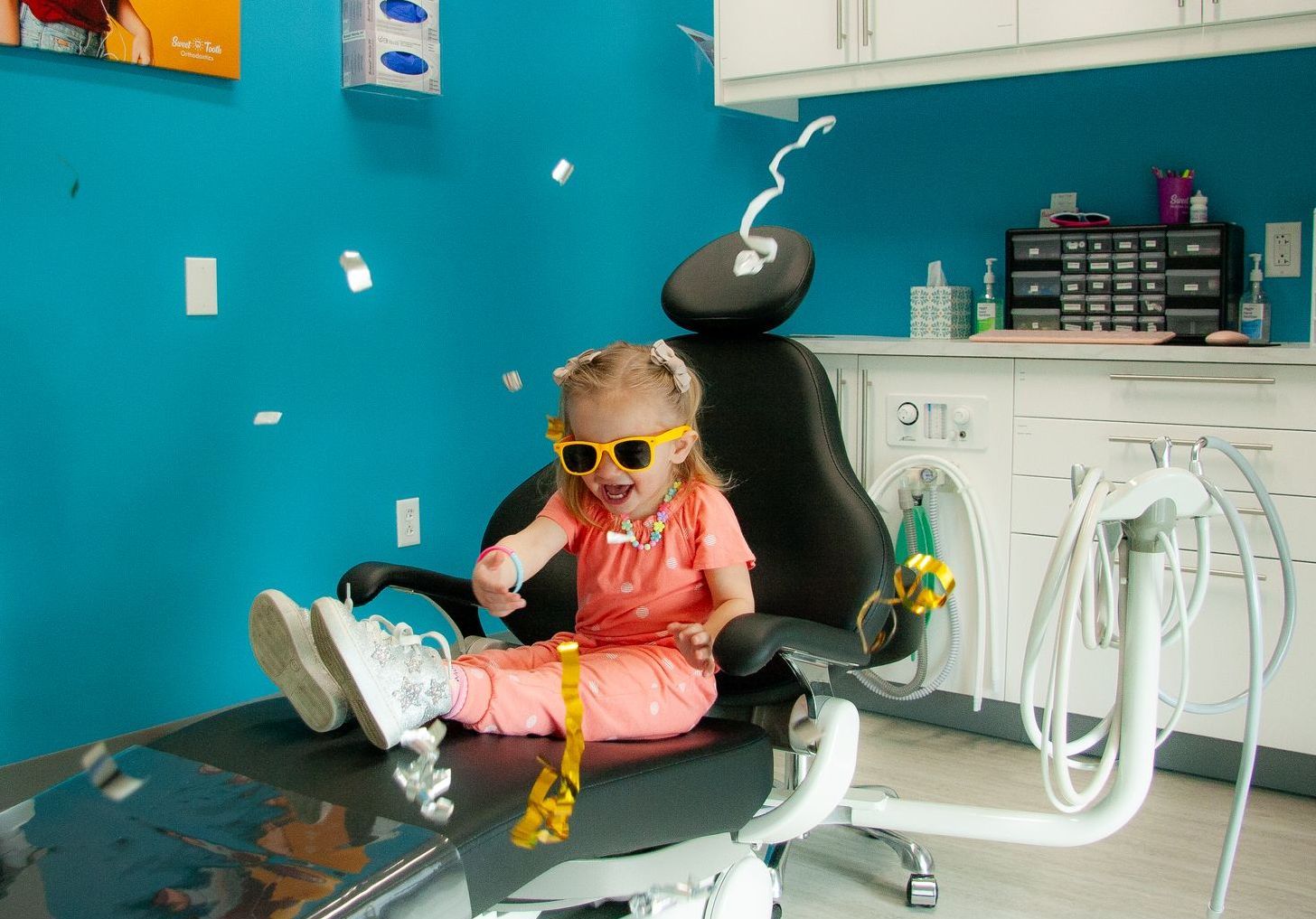 A little girl is sitting on a table while a doctor examines her hand.