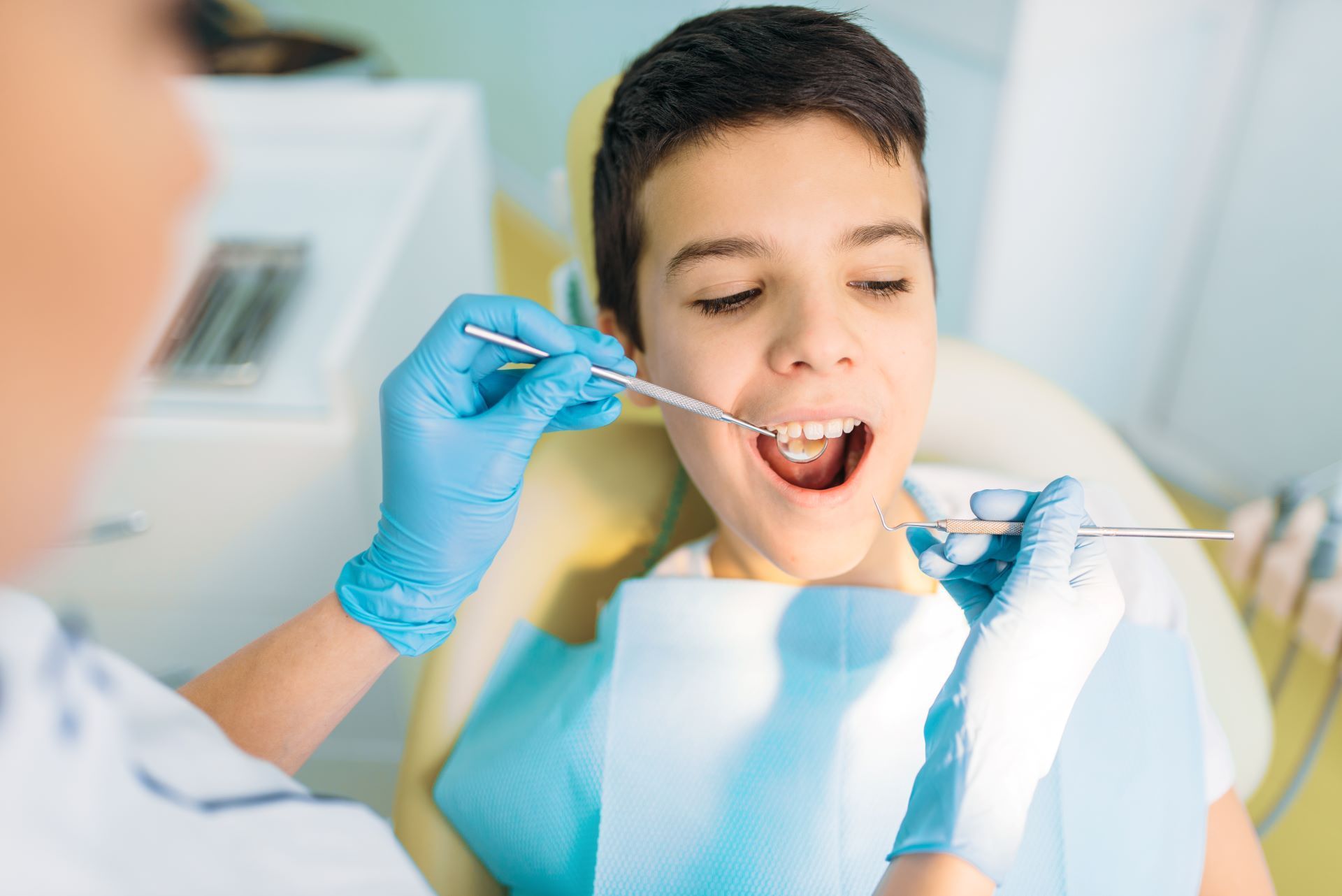 Boy in dental chair with dentist looking in mouth