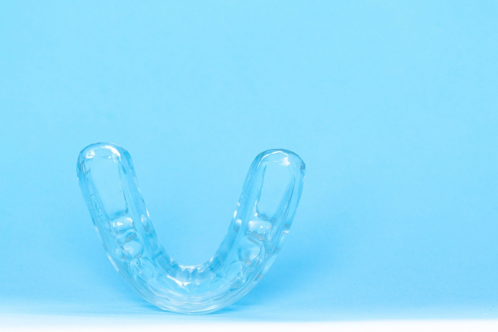 A clear mouth guard is sitting on a blue surface.