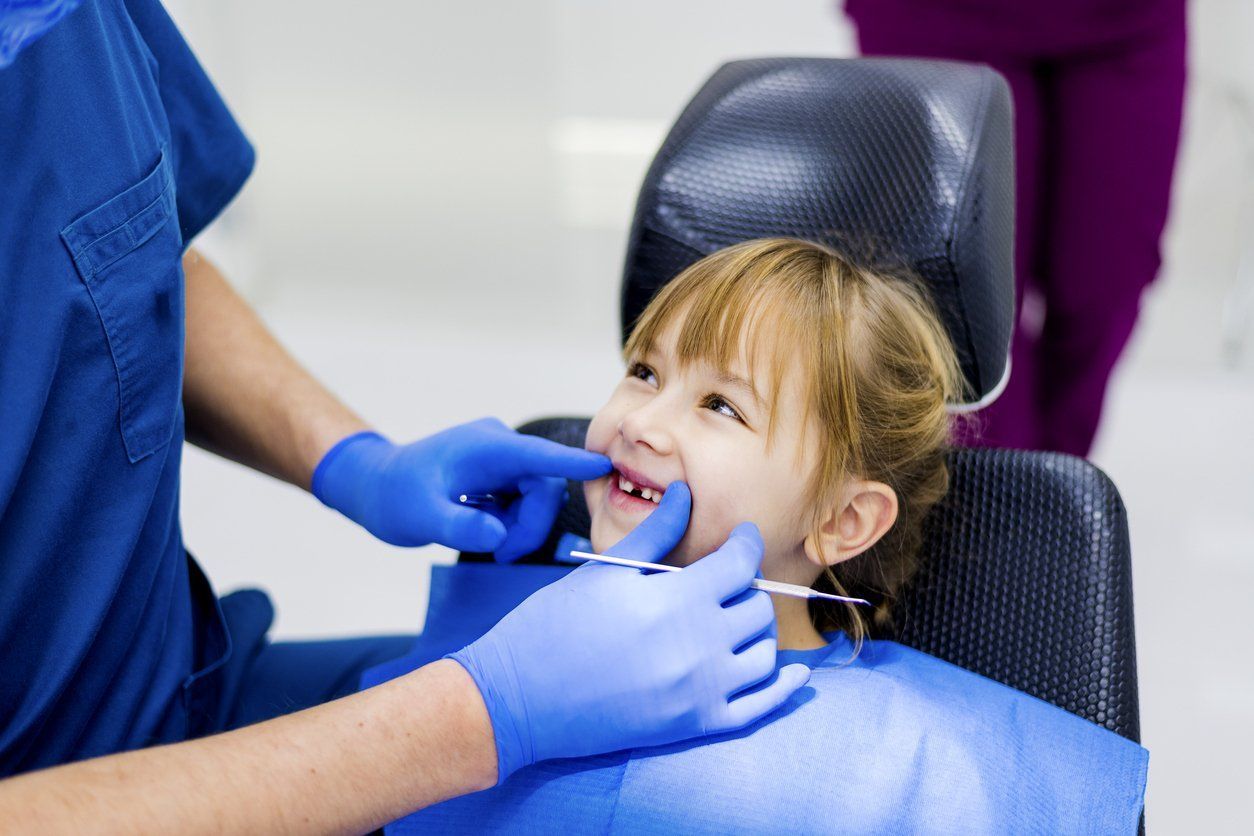 Dentist checking a young girl's teeth - concept of tooth eruption sequence in children.