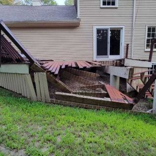 A house with a broken deck and stairs in front of it.