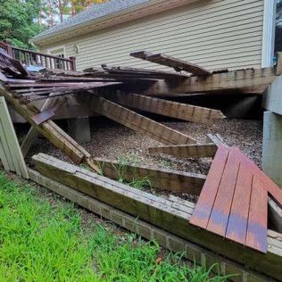 A broken wooden deck is sitting in front of a house.