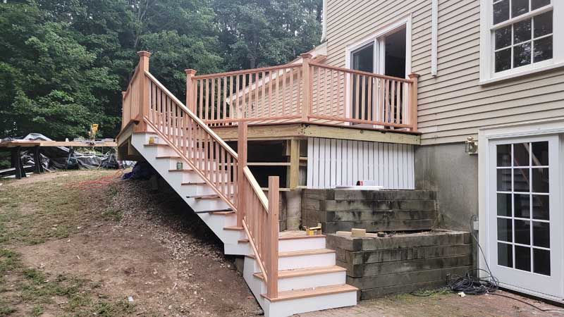A deck with stairs leading up to it is being built in the backyard of a house.