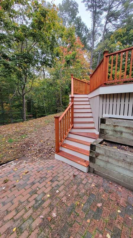 A wooden deck with stairs leading up to it and a brick patio.