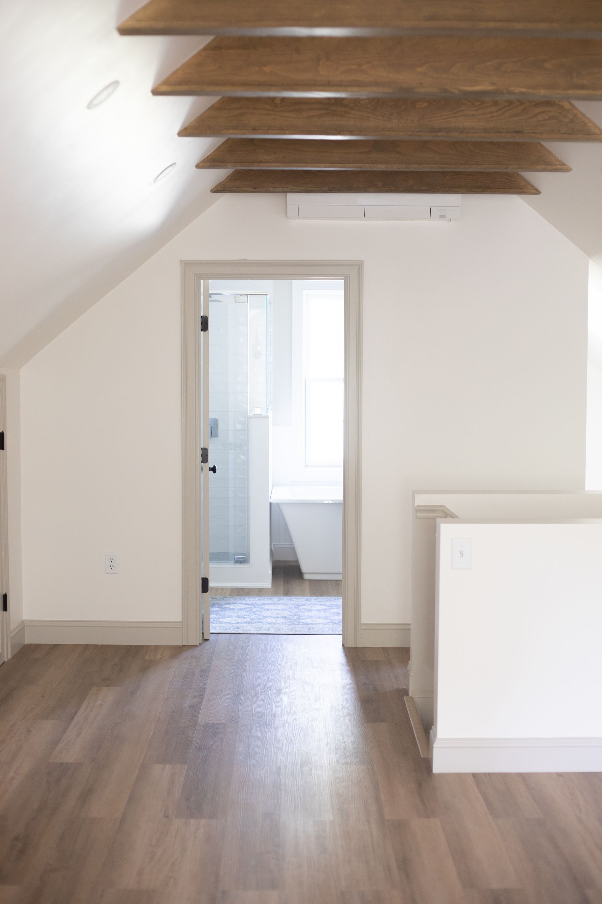 An empty room with hardwood floors and gray walls.