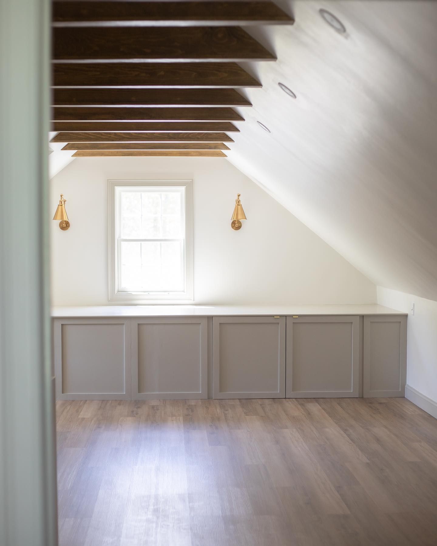 An empty attic with a window and wooden beams.