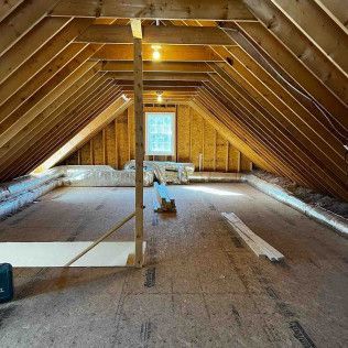 A large attic with wooden beams and a window.