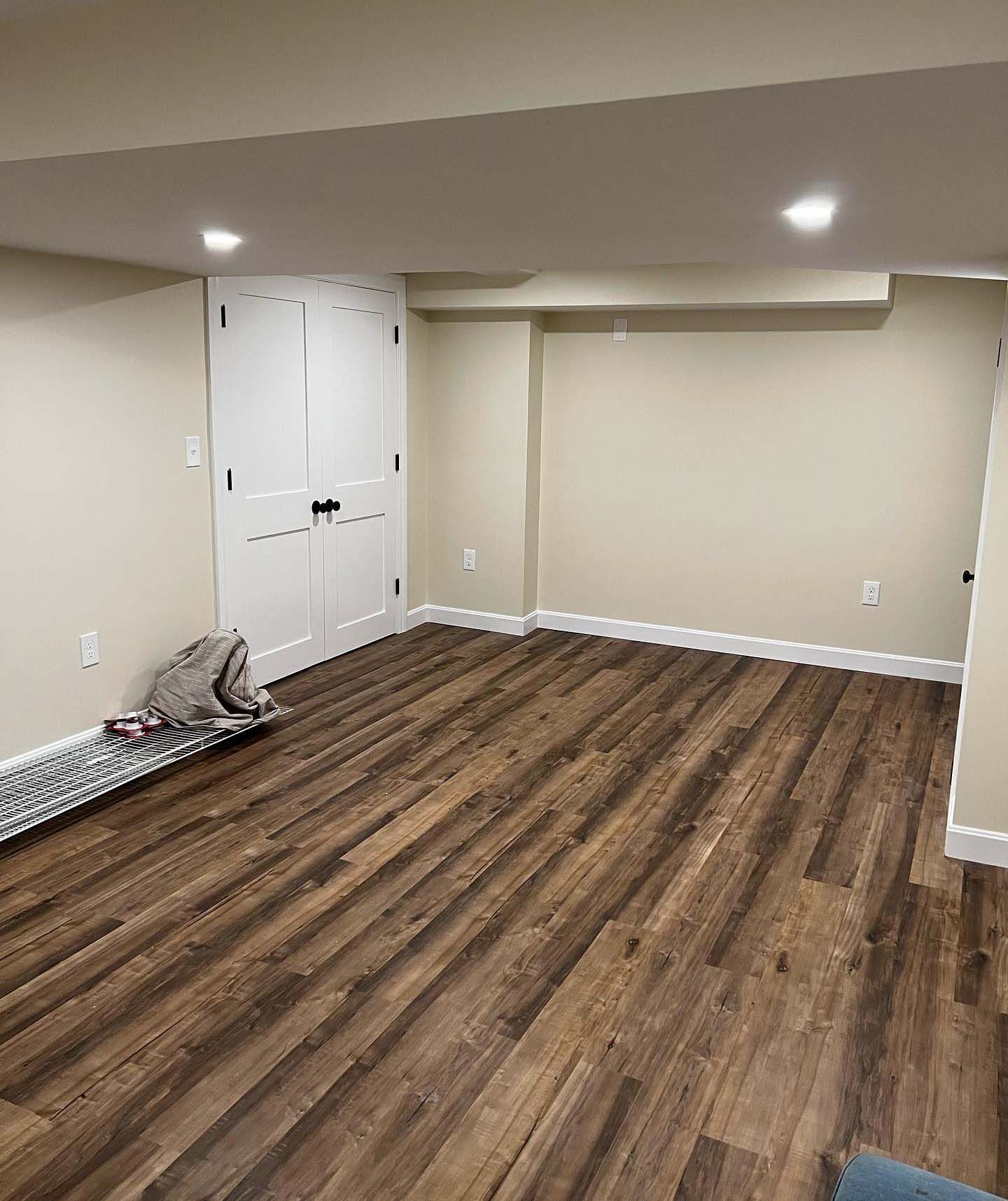 A basement with hardwood floors and white walls.
