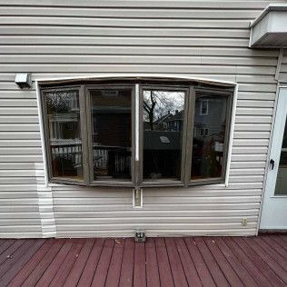 A large window on the side of a house next to a wooden deck.