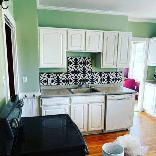 A kitchen with white cabinets , a black stove , a sink , and a dishwasher.