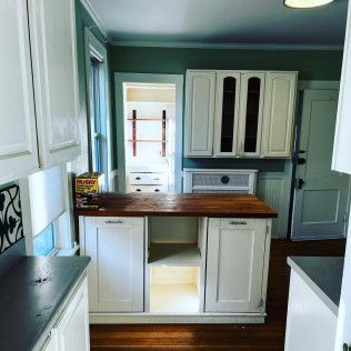 A kitchen with white cabinets and a wooden counter top.