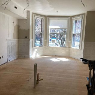 An empty room with wooden floors and a bay window.