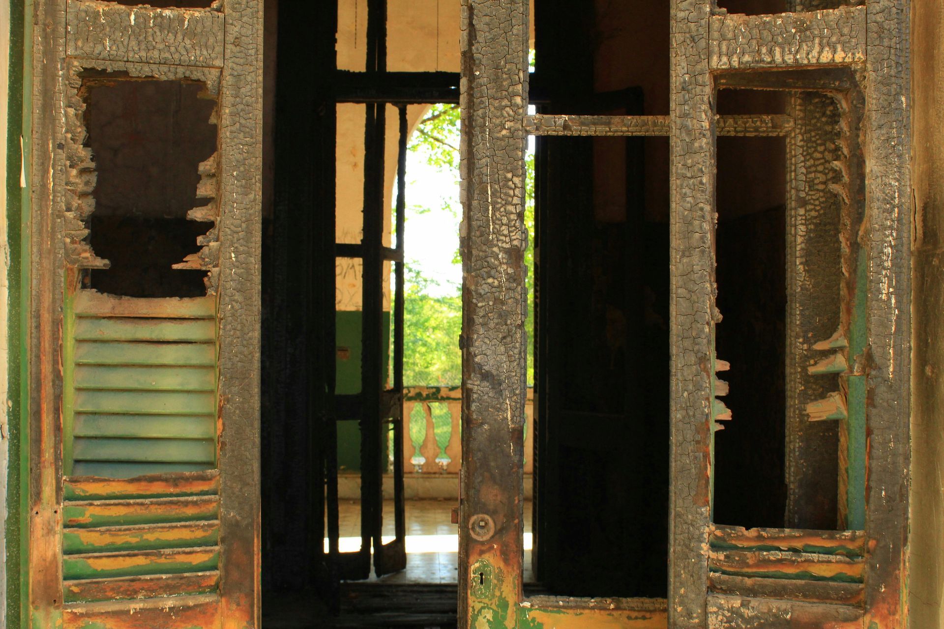 A door with green shutters is open to a balcony