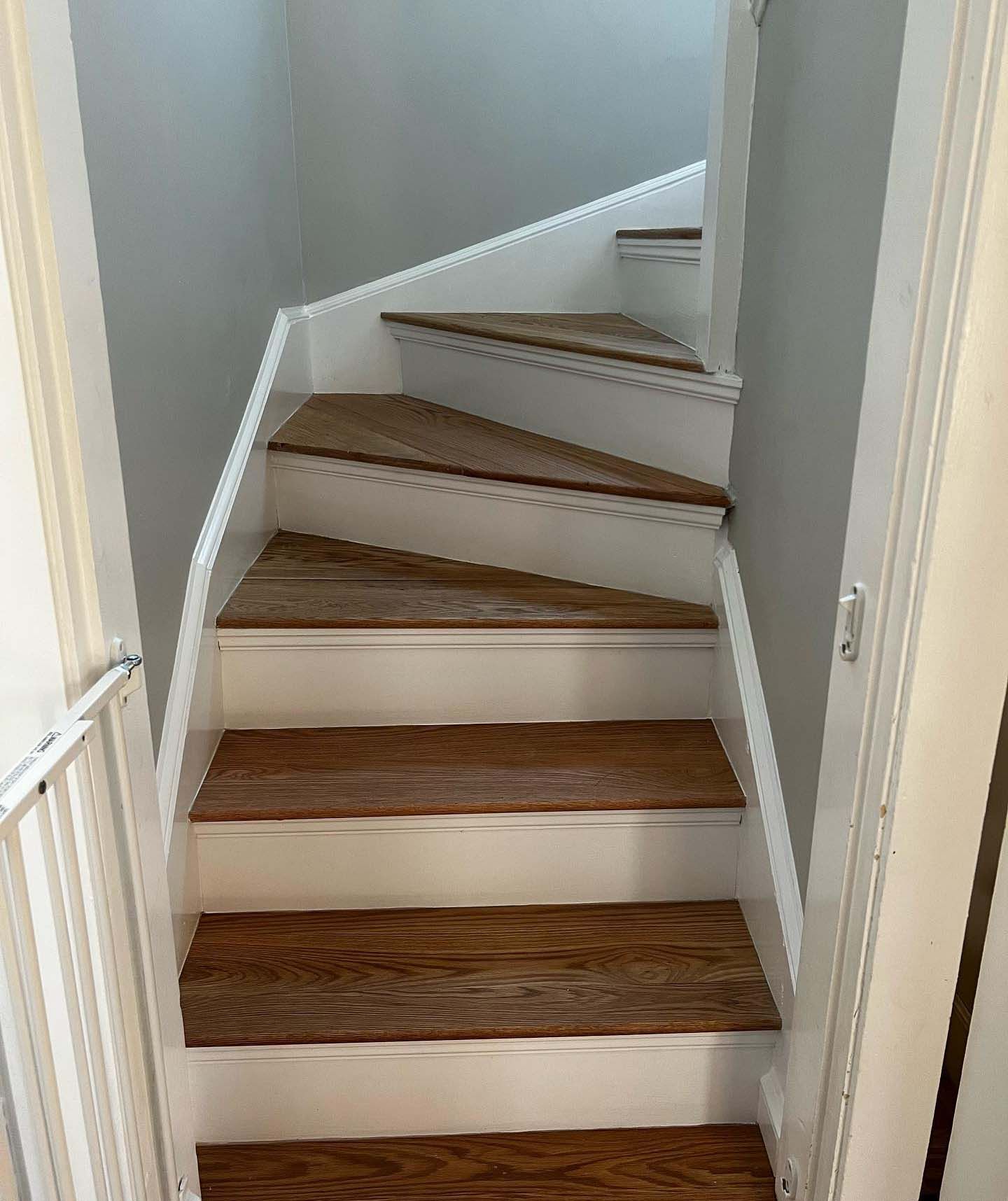 A spiral staircase with wooden steps and white railing in a house.