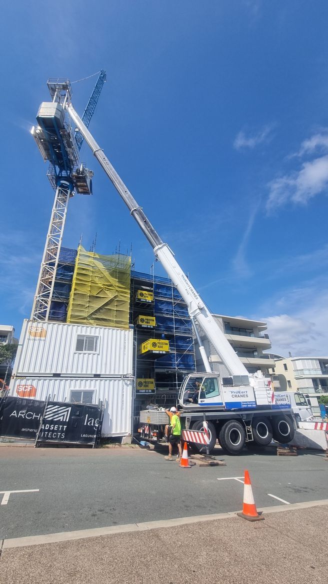 A White Crane Working In Hight On Construction Site — ProCert Cranes In Coolum Beach, QLD