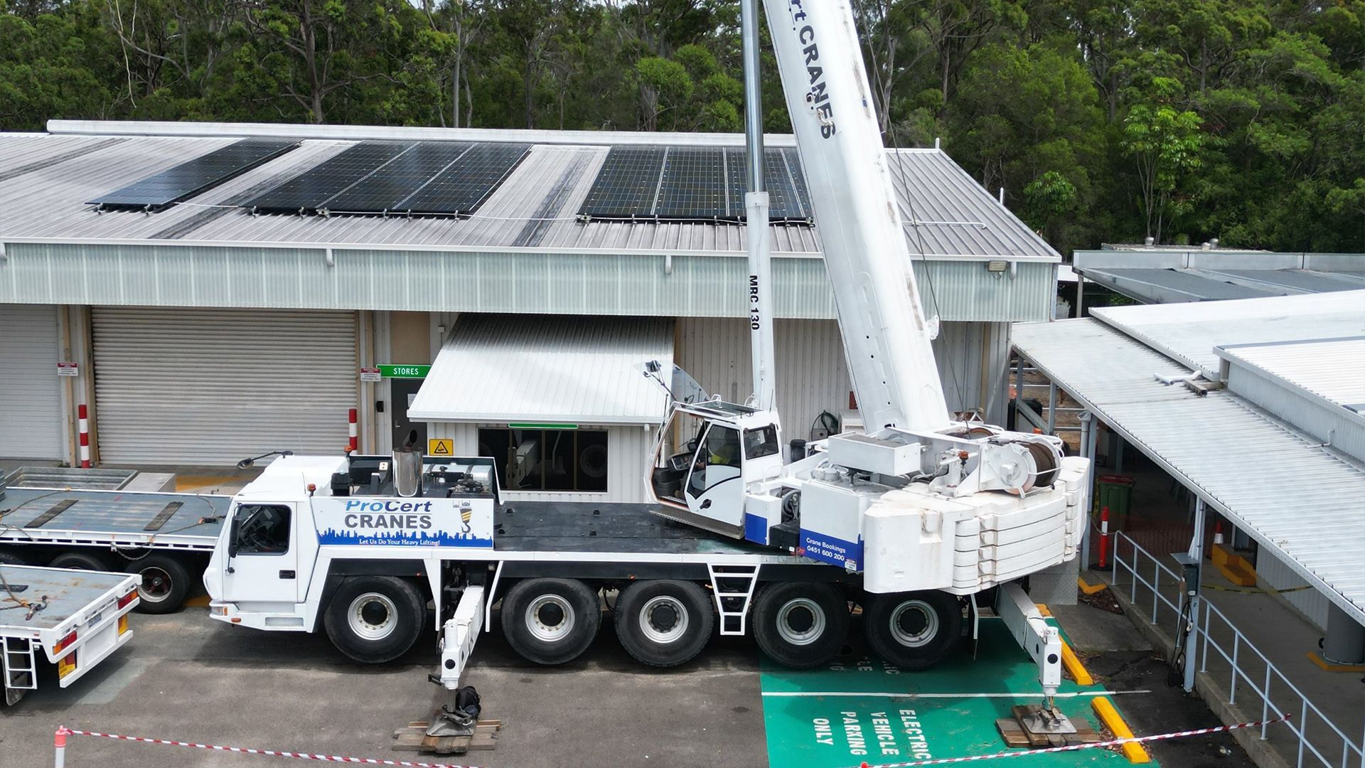 A Large White Crane Lifting Something Near a Building — ProCert Cranes In Coolum Beach, QLD