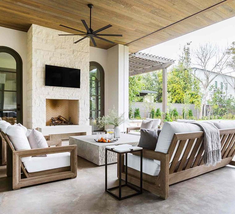 A living room with a fireplace , couch , chairs and a ceiling fan.
