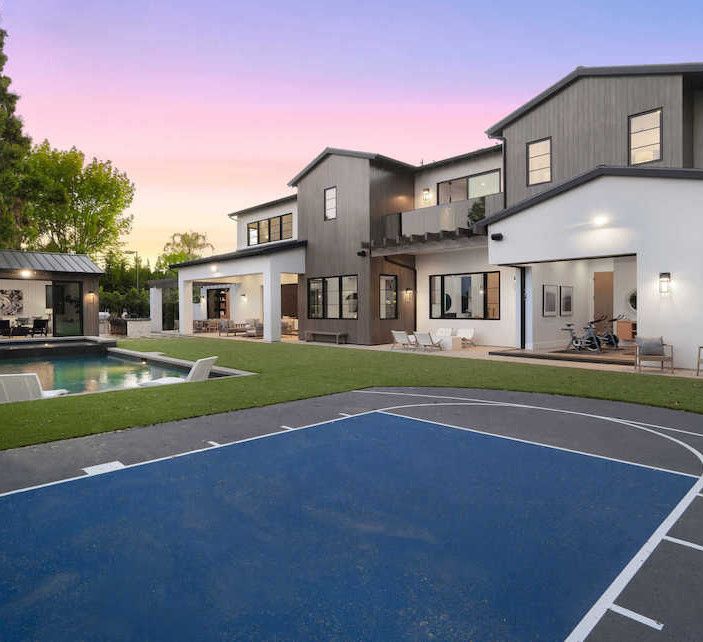 A large house with a basketball court in front of it