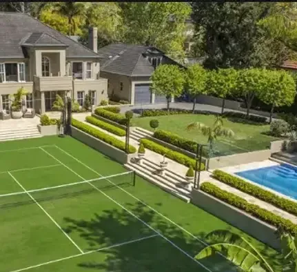 An aerial view of a large house with a tennis court and pool